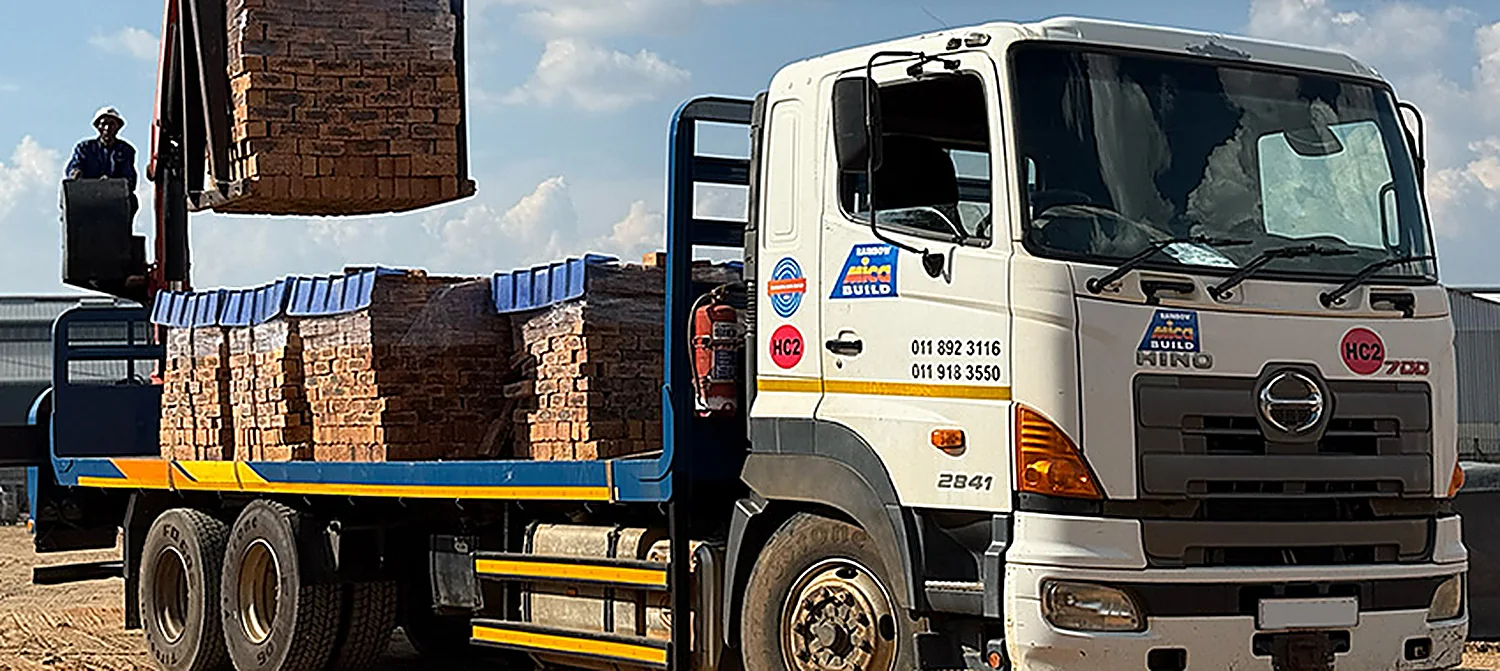 Rainbow Hino crane truck loaded with strapped brick pallets
