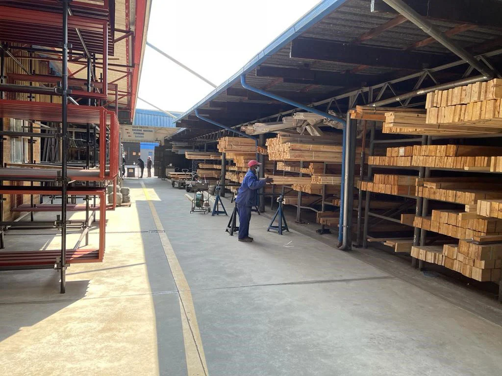 Covered timber aisle with racked SA pine and a yard hand selecting stock